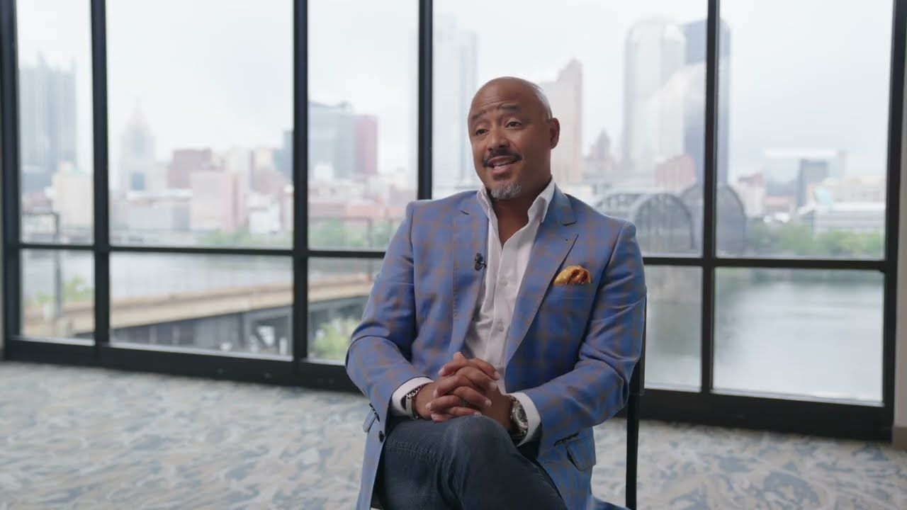 A BEAM leader seated in front of windows overlooking the Pittsburgh skyline